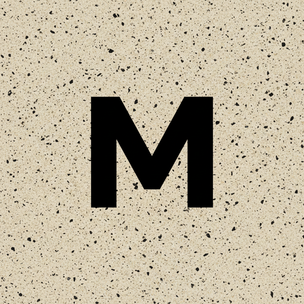 large M in black with a beige backround with black speckles